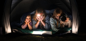 un couple avec ses enfants lit sous une tente avec une lampe